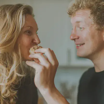 Couple Smiling While Hiding Face With Food